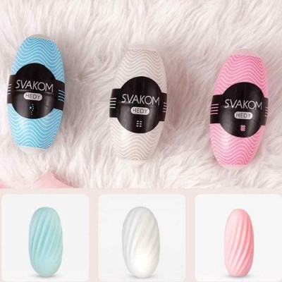 Três dispositivos SVAKOM HEDY azul, branco e rosa com padrões ondulados em superfície felpuda branca