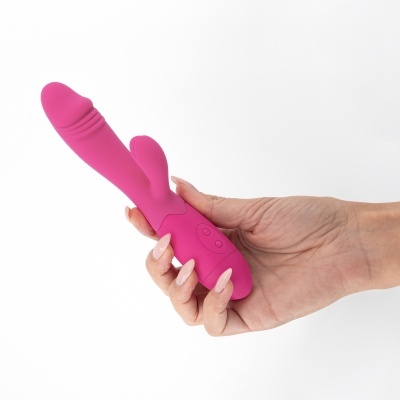Vibrador cor-de-rosa em silicone segurado por uma mão feminina em fundo branco