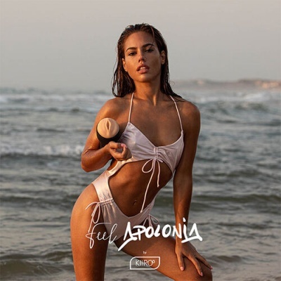 Mulher na praia usando biquíni branco brilhante com recortes laterais segurando um recipiente bege