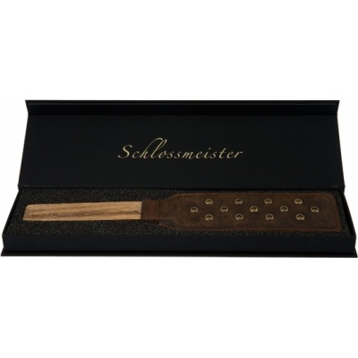 Espátula ou pá em madeira com rebites numa caixa preta com o texto Schlossmeister