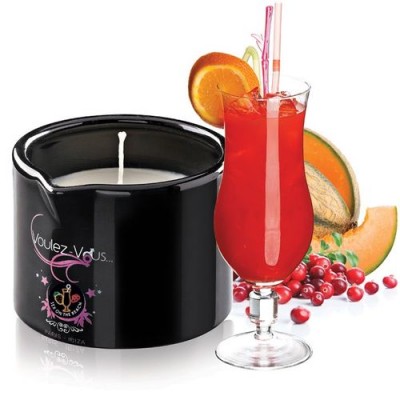 Vela perfumada preta ao lado de cocktail vermelho com frutas