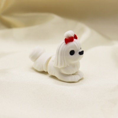 Figurinha de cão branco com laço vermelho sobre tecido branco.