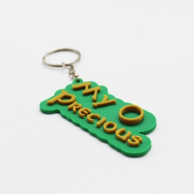 Chaveiro verde com texto amarelo My Precious e anel amarelo com argola metálica