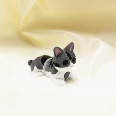 Miniatura de gato cinzento e branco em plástico sobre tecido creme