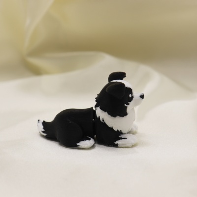 Figura de cão preto e branco em plástico em posição deitada
