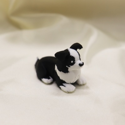 Miniatura de cão preto e branco em plástico sobre tecido branco