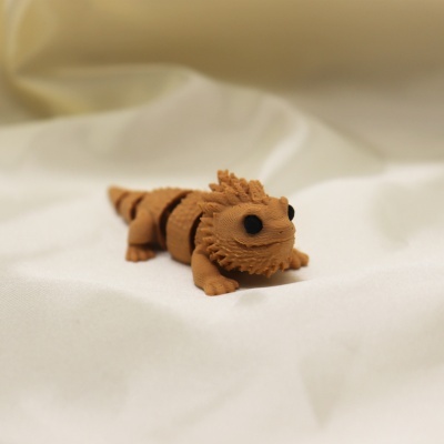 Figura de lagarto castanho com olhos negros sobre tecido branco