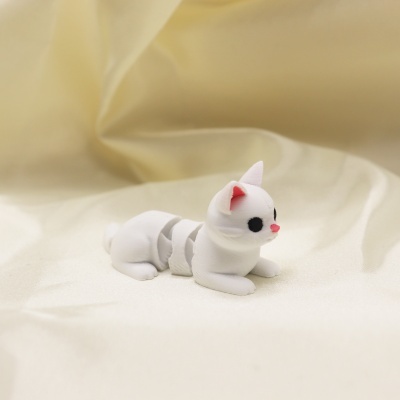 Miniatura de gato branco de plástico sobre tecido creme