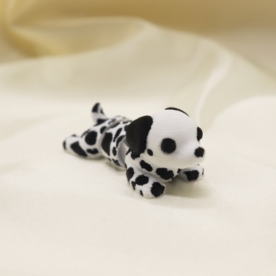 Miniatura de cão dálmata em plástico branco e preto sobre tecido bege.