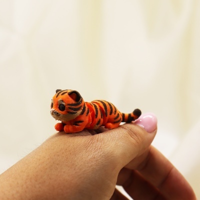 Brinquedo de pelúcia de tigre laranja com listras pretas na mão