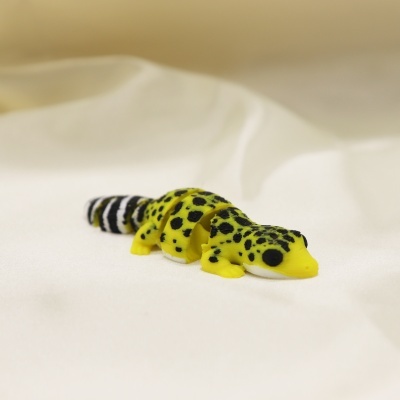 Figura articulada de lagarto amarelo com manchas pretas e cauda listrada preto e branco