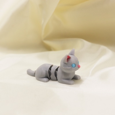 Boneco de gato cinzento em material plástico sobre tecido creme.