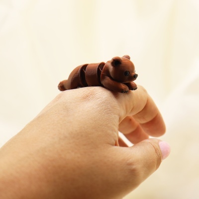 Anel em forma de urso marrom articulado num dedo