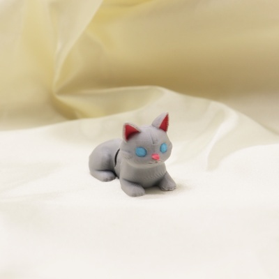 Miniatura de gato cinzento com olhos azuis e nariz rosa sobre tecido branco