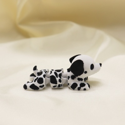 Figura de cachorro articulado preto e branco sobre tecido creme