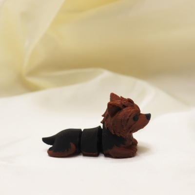 Figura de cão em plástico preto e castanho sobre tecido branco