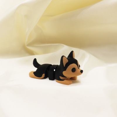 Boneco pequeno de cão preto e castanho sobre tecido branco