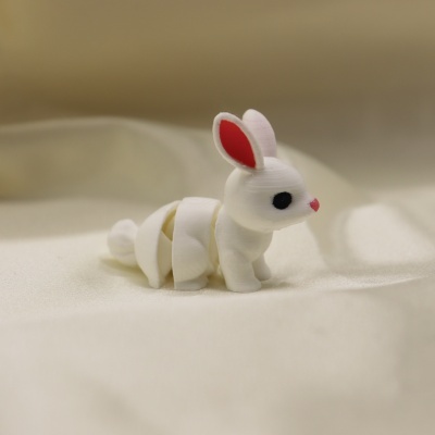 Miniatura de coelho branco com orelhas vermelhas, olhos pretos e nariz rosa sobre tecido branco