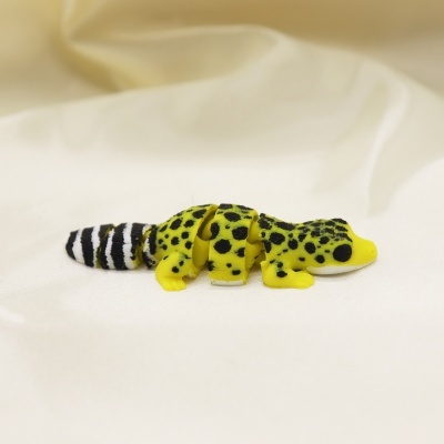 Brinquedo de lagarto articulado amarelo e preto numa superfície branca