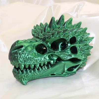 Crânio de dragão verde metálico decorativo sobre tecido branco
