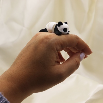 Anel panda a dormir preto e branco no dedo de uma mão