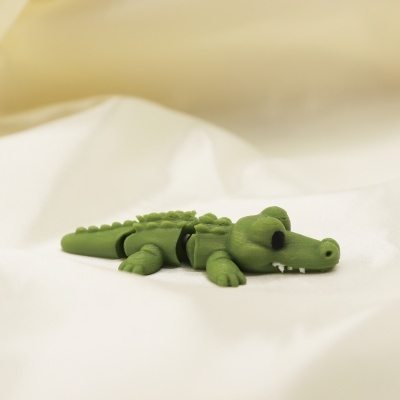 Miniatura de crocodilo verde articulado sobre tecido branco