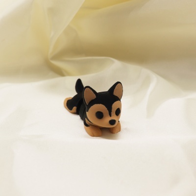 Figura digital pequena de cão preto e castanho sobre tecido branco.