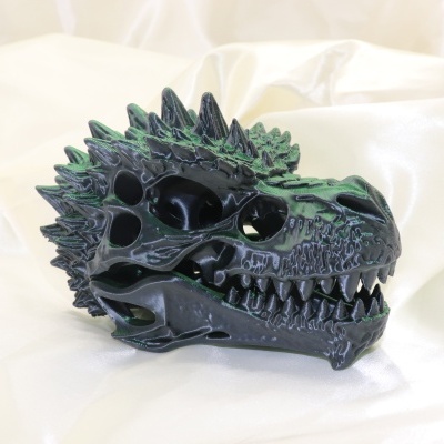 Escultura de crânio de dragão preto sobre tecido branco brilhante