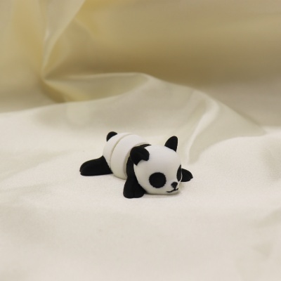 Brinquedo panda branco e preto deitado sobre tecido branco brilhante