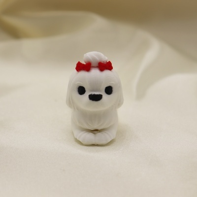 Figura pequena de cão branco com laços vermelhos sobre tecido branco