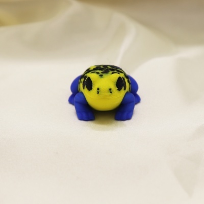 Figura decorativa de rã amarela e azul sobre tecido branco