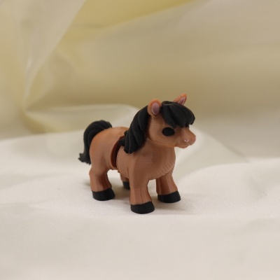 Brinquedo de cavalo castanho com crina preta sobre tecido