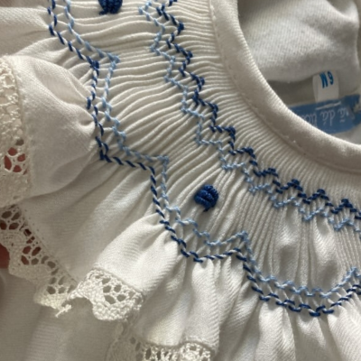 Blusa branca bordada com padrão azul e renda