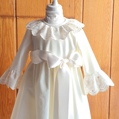 Vestido branco de criança com gola e punhos de renda e laço de cetim