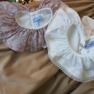 Dois babetes para bebé, um floral rosa e branco e outro branco com rendas