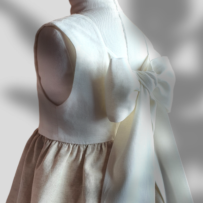 Vestido infantil bege e branco com laço volumoso em manequim