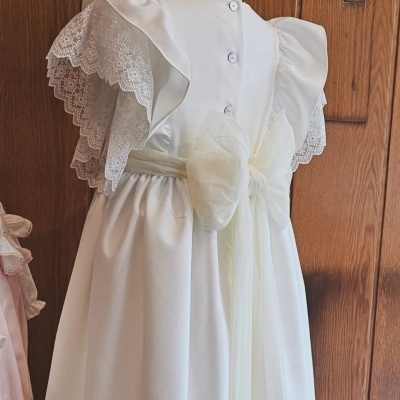 Vestido branco para criança com renda e laço em fundo de madeira