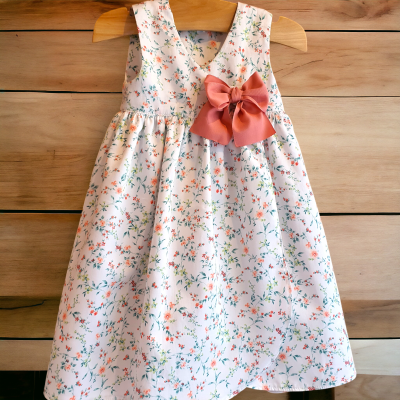 Vestido infantil branco com padrão floral e laço rosa