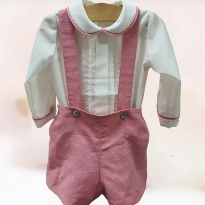 Roupa de bebé com camisa branca e calções rosa com alças e botões.