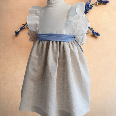 Vestido infantil bege, branco e azul com mangas rendadas num manequim