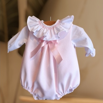 Macacão cor de rosa claro com gola frisada branca e laço rosa.