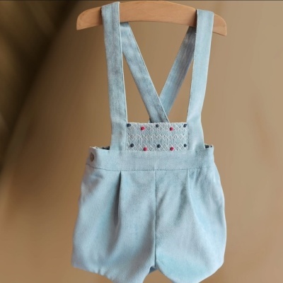 Peto curto azul claro para bebé com alças cruzadas e bordados coloridos