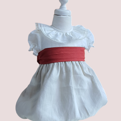 Vestido branco de bebé com faixa vermelha em manequim