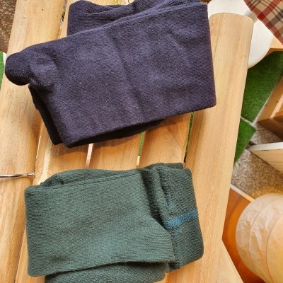 Duas meias-calças ou leggings azul escuro e verde escuro sobre superfície de madeira clara.