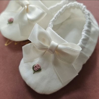Sapatinhos de bebé brancos com laço de cetim e bordado de flor cor de rosa