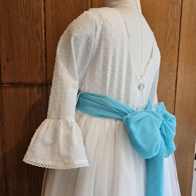 Vestido branco texturado com laço azul claro na cintura exibido em manequim.