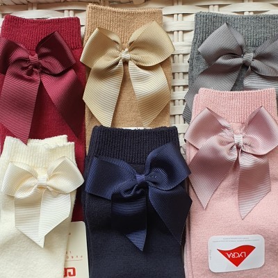 Meias de malha com grandes laços em várias cores dispostas sobre superfície de verga branca.