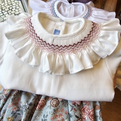 Roupa infantil branca com folhos e bordados, saia floral azul e rosa