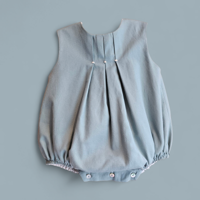 Macacão cinza azulado para bebé com botões e pregas.