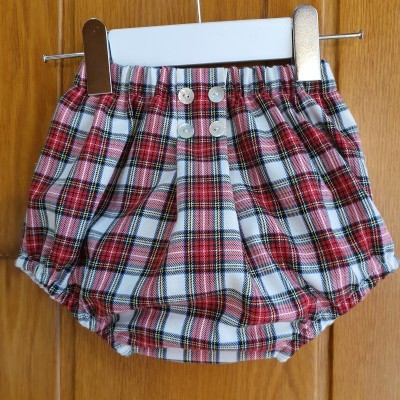 Calção bebé xadrez com botões pendurado numa cabide branca